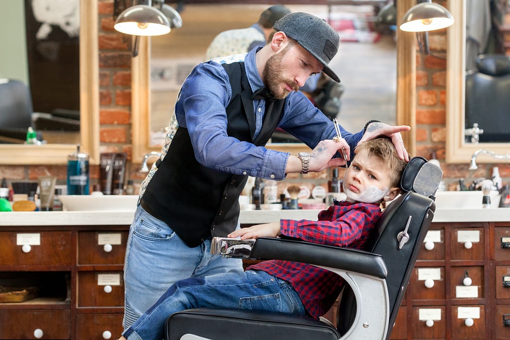 Ein Junge wird von einem Barber rasiert