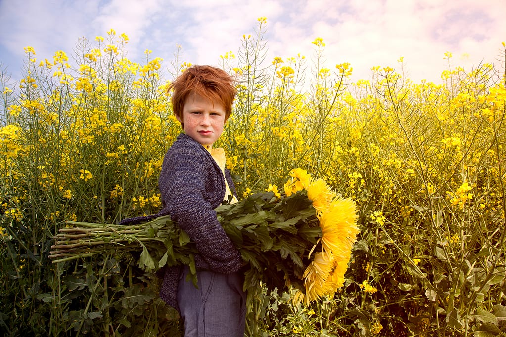 Kids Fotoshooting - ein JUnge mit gelben Blumen im gelben Rapsfeld