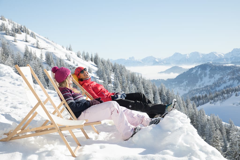 Zwei Frauen liegen in einem Liegestuhl im Schnee